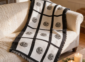Nine panel sublimation blanket with black grid border and botanical medallion print draped over a cream sofa in a warm farmhouse living room with candles and greenery