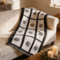 Nine panel sublimation blanket with black grid border and botanical medallion print draped over a cream sofa in a warm farmhouse living room with candles and greenery