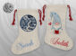 Two natural linen Christmas stockings with red drawstring ties — one with a blue circular winter village scene personalised with the name Sarah, the other with a whimsical Christmas gnome personalised with the name Judith in red script