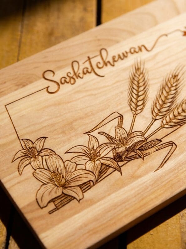 Close-up laser-engraved Saskatchewan design on Canadian maple cutting board showing wheat and prairie lily detail